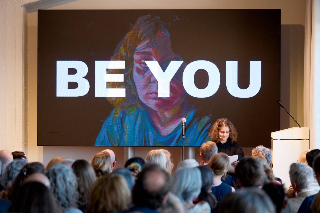 Eine junge Frau sitzt auf der Bühne und zeichnet.