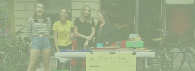 Vier Schülerinnen stehen lachend an einem Infostand, Foto mit grünem Overlay