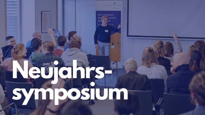 Foto von einem jungen Mann, der einen Vortrag hält. Darauf ein blaues Overlay mit dem Text: Neujahrssymposium.