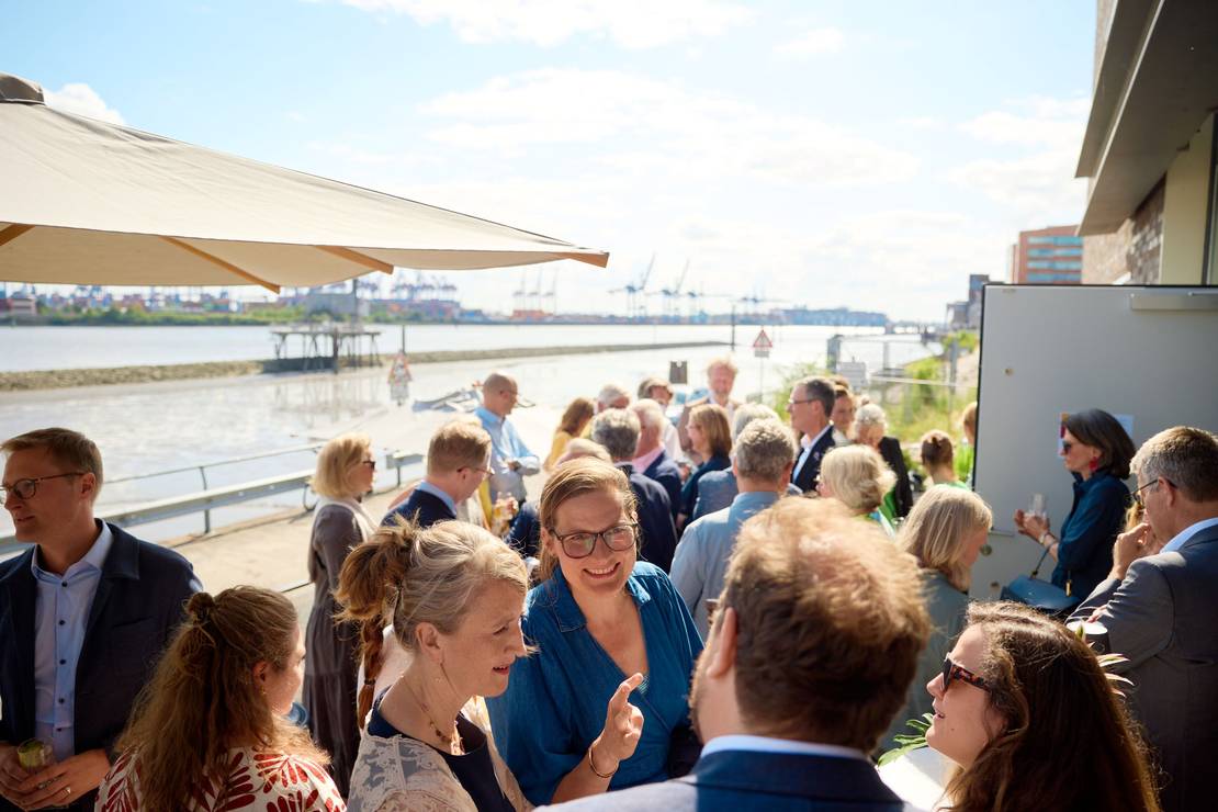 Foto von vielen Menschen, die scích draußen vor der Stiftung unterhalten.