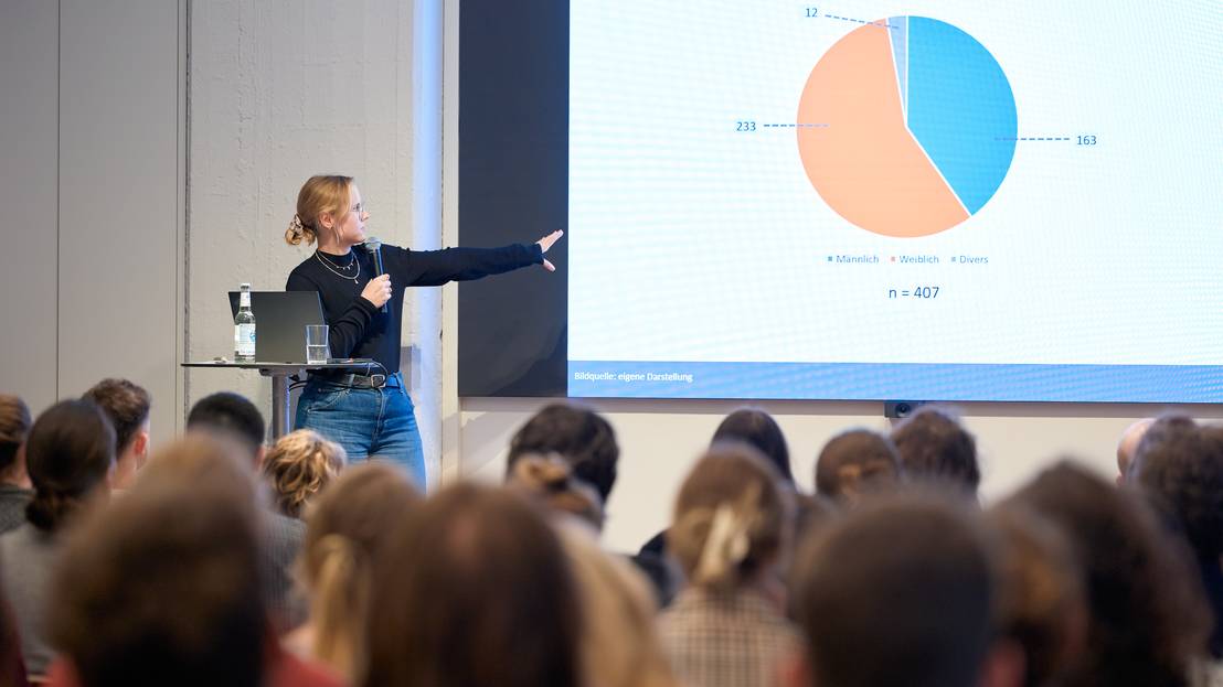 eine Stipendiat:in hält einen wissenschaftlichen Powerpoint-Vortrag vor Zuschauer:innen